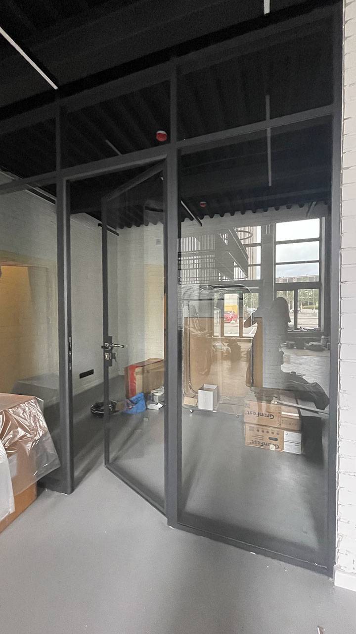 Перегородки и двери в офисе из черного алюминиевого каркаса и стекла